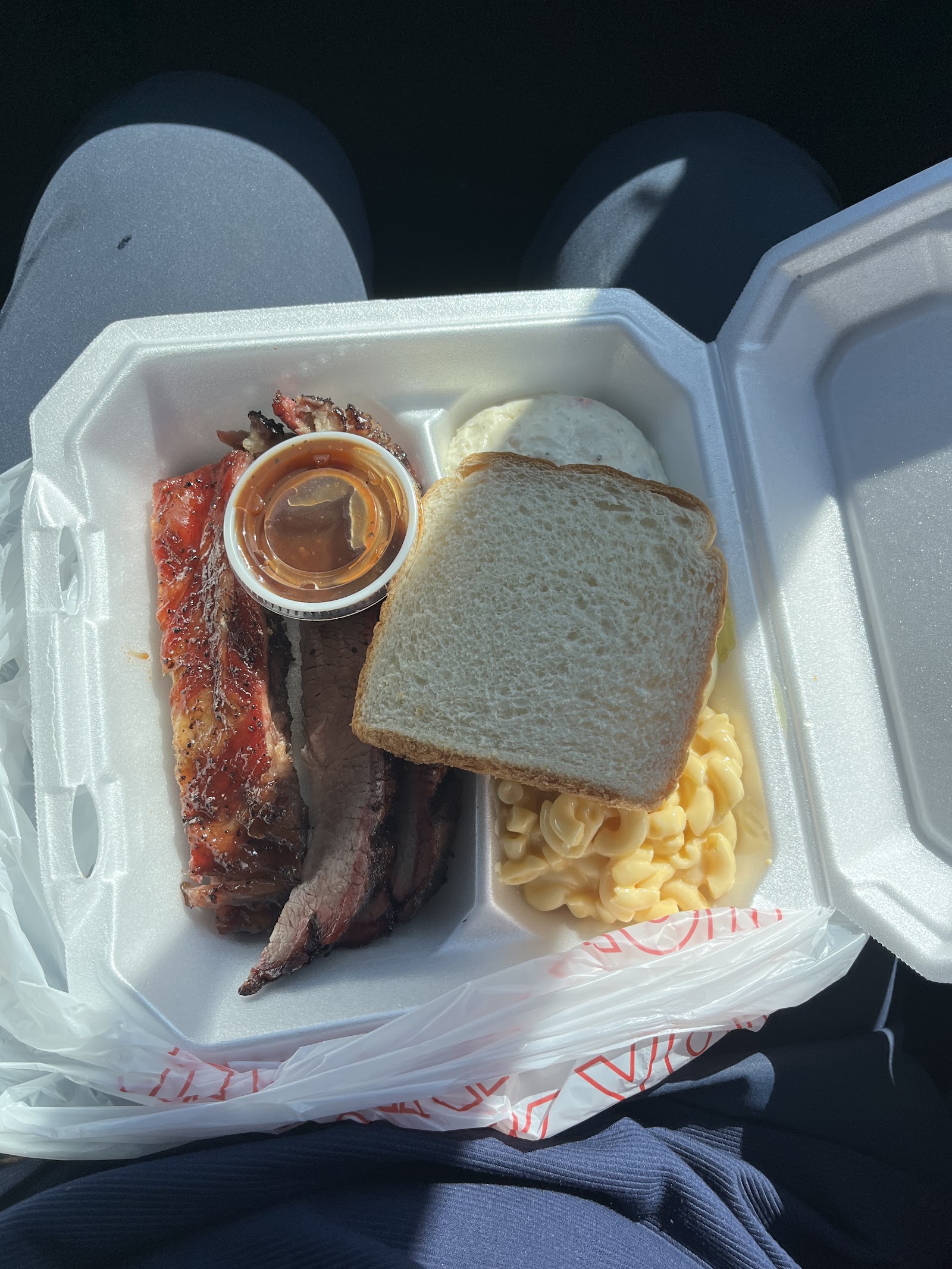 To-go container with smoked brisket, ribs, white bread and mac and cheese