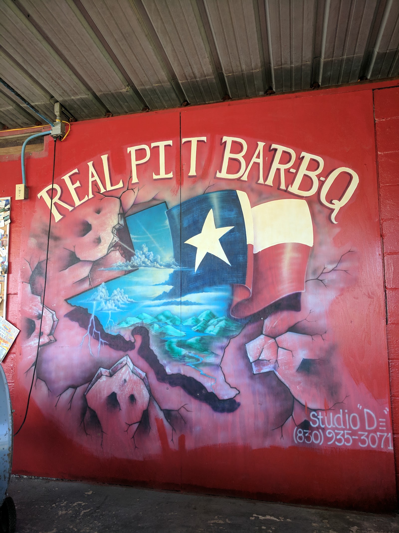Mural of the Real Pit Bar-B-Q logo with a Texas flag painted on the interior wall