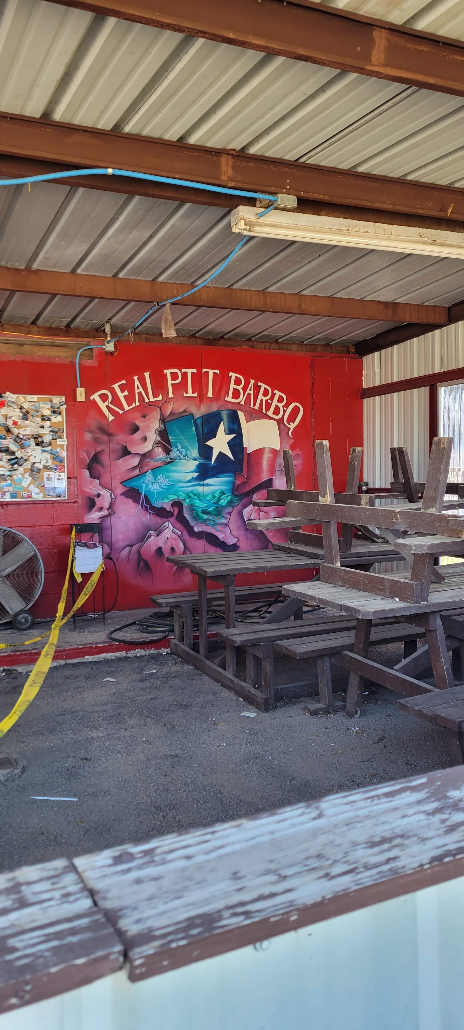 Covered picnic table seating area with Real Pit Bar-B-Q mural